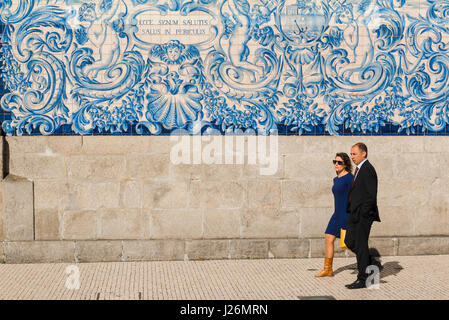 Portugal tiles Porto, view of a Portuguese couple walking past the Igreja do Carmo church whose wall is richly decorated in blue azulejos tiles, Porto Stock Photo