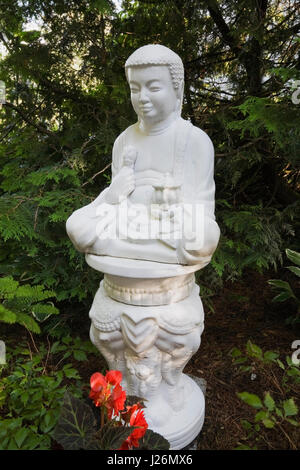 Buddhist style statuette in landscaped residential backyard garden in summer, Les Jardins du Grand Duc garden, Saint-Raymond, Portneuf, Quebec, Canada Stock Photo