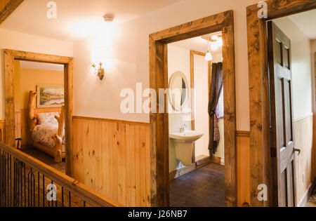 Rustic bed in the main upstairs guest room and bathroom inside a residential log home Stock Photo