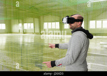 Architect with VR visor exploring industrial building environment with blueprint lines overlaying the real scenario Stock Photo
