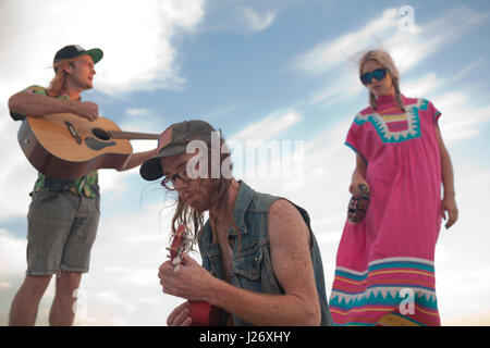 Friends playing music together on a beach Stock Photo