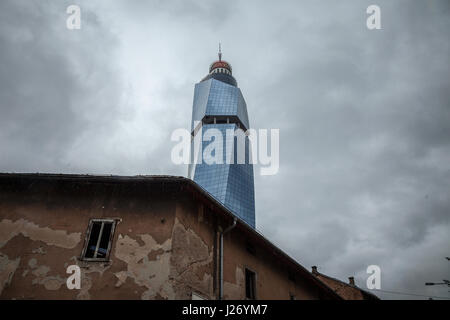 SARAJEVO, BOSNIA HERZEGOVINA - APRIL 16, 2017: Avaz Twist Tower in the rain, with a destroyed old house in front. Avaz Tower is one of the main symbol Stock Photo