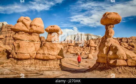 Panoramic view of male person hiking amidst stunning Hoodoos sandstone formations in famous Goblin Valley State Park in summer, Utah, USA Stock Photo