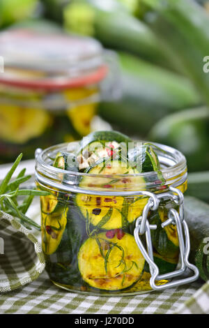 Fried zucchini slices pickled in olive oil with herbs and filled in a canning jar Stock Photo