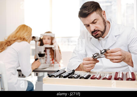 Nice expert working on set of trial glasses for little girl Stock Photo