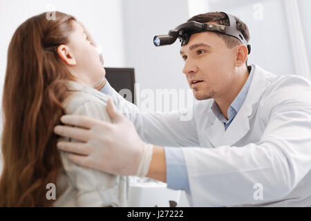 Serious medical worker treating his little patient Stock Photo