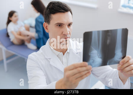 Serious confident surgeon studying an X ray photo Stock Photo