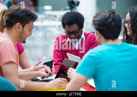 Multiracial group of young students studying together. High angle shot of young people sitting at the table. Stock Photo