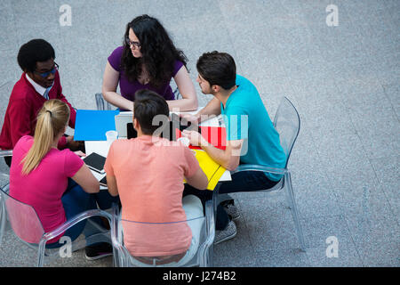 Multiracial group of young students studying together. High angle shot of young people sitting at the table. Stock Photo