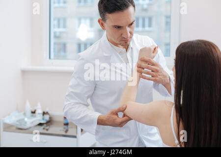 Nice male doctor holding his patients hand Stock Photo