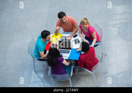 Multiracial group of young students studying together. High angle shot of young people sitting at the table. Stock Photo