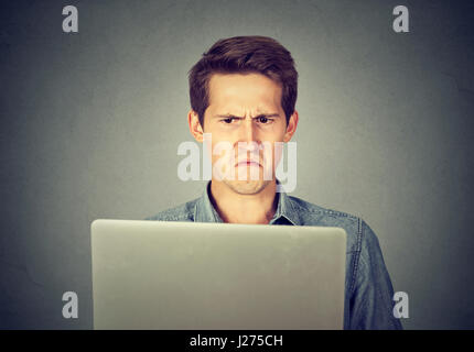 Frustrated disgusted young man looking at his laptop displeased with email Stock Photo