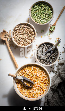 Brown lentil,French lentil Split dry green peas and Split chana dal in individual ceramic bowls on a marble backdrop on top down ingredient shot Stock Photo