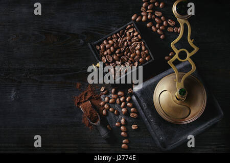 Roasted coffee beans and grind coffee in wood box with vintage coffee grinder and scoop over black wooden burnt background. Top view with space. Stock Photo