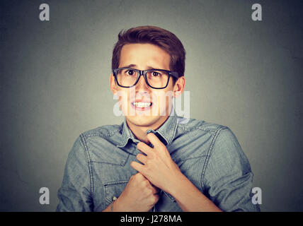 Nervous stressed young man student feels awkward looking at camera anxiously craving something isolated gray wall background. Human emotion face expre Stock Photo