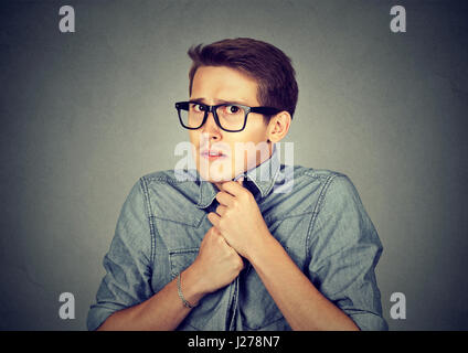 Nervous stressed young man student feels awkward looking at camera anxiously craving something isolated gray wall background. Human emotion face expre Stock Photo