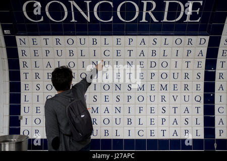 Passenger reading words constructed from the tiles at the Place de la Concorde station in Paris, France. Stock Photo