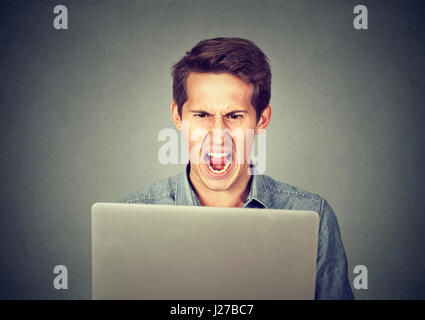 Angry furious business man screaming at computer. Negative human emotions, facial expressions, feelings, aggression, anger management issues concept Stock Photo