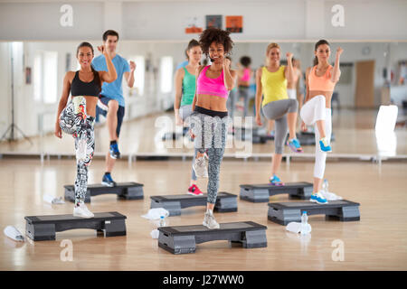 Exercisers in colorful sportwears with young curly female instructor on group training Stock Photo