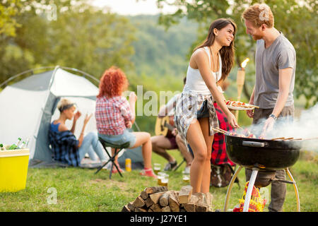 Male and female lovingly look each other while baked barbecue in green nature Stock Photo