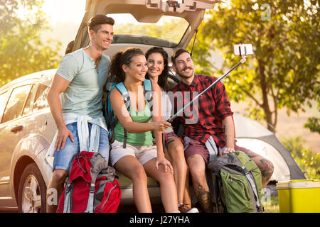 Group of young friends in countryside on camping trip taking selfie using smartphone Stock Photo