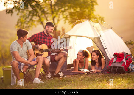 Romantic time on camping two men singing girls in the tent Stock Photo