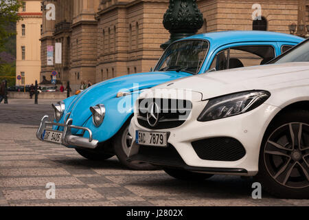 PRAGUE, CZECH REPUBLIC - APRIL 21, 2017: A small blue vintage Volkswagen Beetle car next to a big white Mercedes, parked in front of the Rudolfinum co Stock Photo