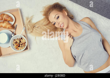 Young beautiful woman having breakfast in bed. Stock Photo