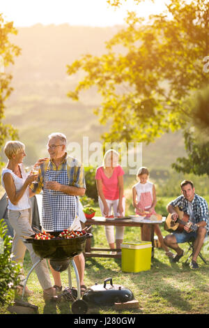 smiling grandparents drinking wine and enjoying picnic with family Stock Photo