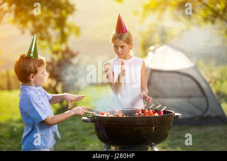 children having a barbecue party on camping Stock Photo