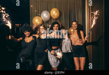 Shot of group of girls celebrating new years eve at the nightclub. Group of female friends partying in pub with sparklers. Stock Photo