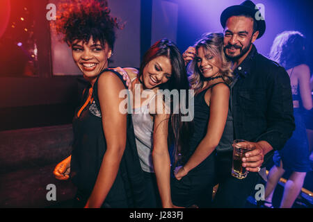 Young man and woman enjoying a party at nightclub. Group of friends dancing at disco club. Stock Photo