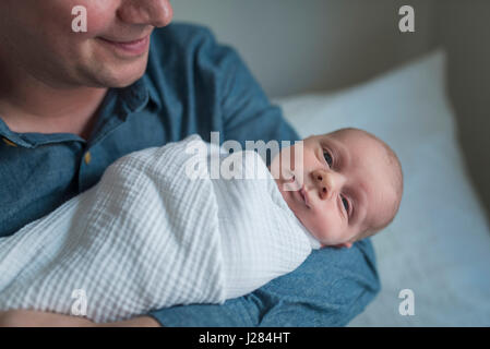 Portrait of cute newborn baby boy being carried by father at home Stock Photo