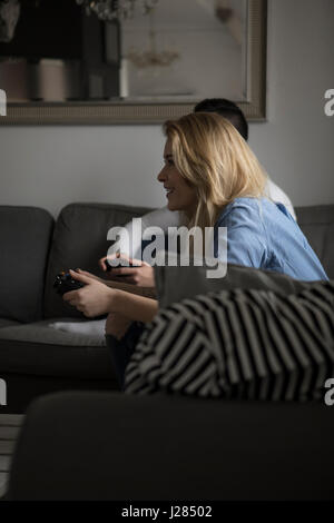 Happy couple playing video game on sofa at home Stock Photo