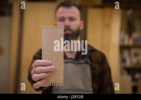 Carpenter holding wooden plank in workshop Stock Photo