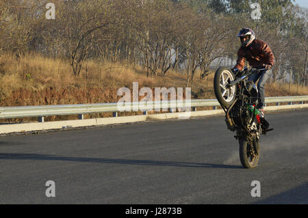 Stunt motorcycle rider performing at a local road near Pune, Maharashtra Stock Photo