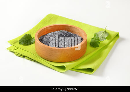 black poppy seeds in wooden bowl on green placemat Stock Photo