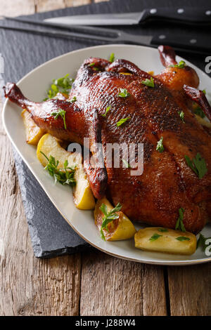 Delicious whole baked duck with apples close-up on a platter on the table. vertical Stock Photo