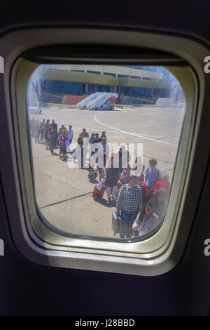 People queueing to board aircraft seen through window Stock Photo