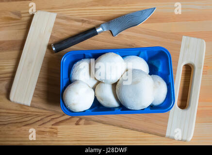 Button mushrooms and a high-end paring knife and wooden cutting board Stock Photo