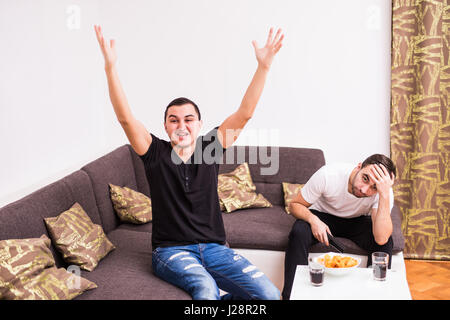 friendship, sports and entertainment concept - happy male friends supporting football team at home Stock Photo