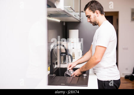 young happy man doing the dishes smiling confident and relaxed enjoying doing domestic work Stock Photo