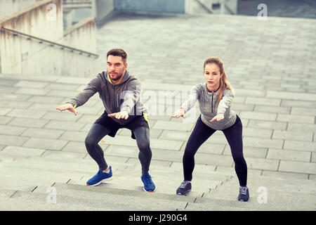 couple doing squats and exercising outdoors Stock Photo