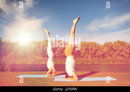 couple making yoga headstand on mat outdoors Stock Photo