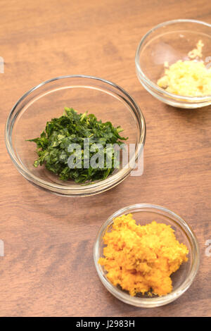 Garlic, parsley and orange rind in measured bowls for a food dish preparation Stock Photo