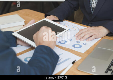 Businessman discussing with financial analyst business development strategy project chart document and using modern digital tablet touchpad Stock Photo