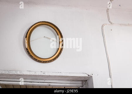 Old wooden empty oval painting frame on the white wall over the doors Stock Photo