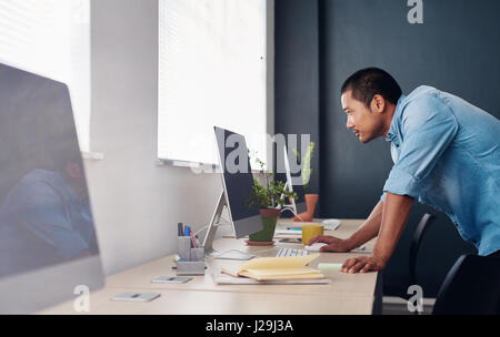 Focused Asian designer working on a computer in an office Stock Photo