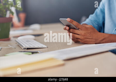 Young designer reading text messages at his office desk Stock Photo