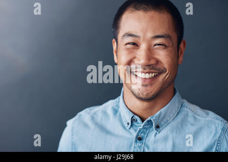 Smiling young Asian designer standing in an office Stock Photo